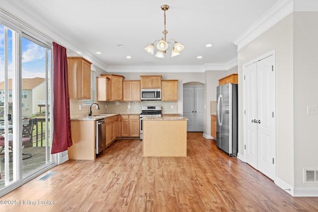 9006 Big Boulder Dr, Louisville, KY 40291 - kitchen with appliances with stainless steel finishes, a chandelier, a kitchen island, tasteful backsplash, and light wood-type flooring