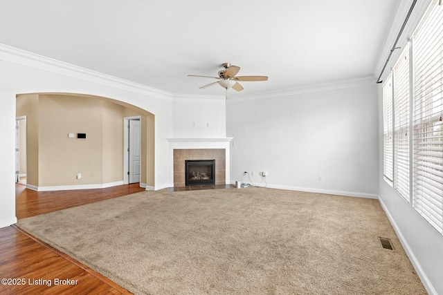 9006 Big Boulder Dr, Louisville, KY 40291 - unfurnished living room featuring a ceiling fan, crown molding, a tiled fireplace, and arched walkways
