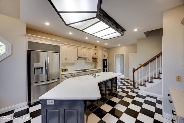 7202 Doe Crest Ct, Prospect, KY 40059 - kitchen featuring appliances with stainless steel finishes, dark floors, light countertops, a center island with sink, and recessed lighting