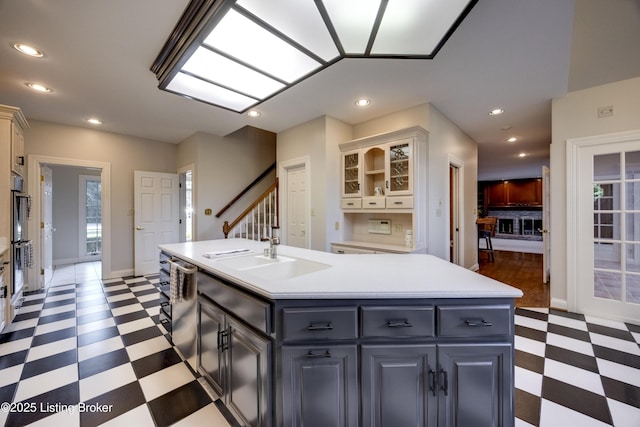7202 Doe Crest Ct, Prospect, KY 40059 - kitchen with light floors, an island with sink, light countertops, glass insert cabinets, and plenty of natural light
