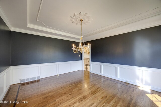 7202 Doe Crest Ct, Prospect, KY 40059 - unfurnished room with a chandelier, a decorative wall, a raised ceiling, crown molding, and wood finished floors