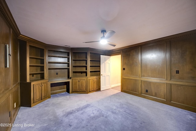 7202 Doe Crest Ct, Prospect, KY 40059 - unfurnished living room with built in study area, ceiling fan, light colored carpet, ornamental molding, and built in shelves