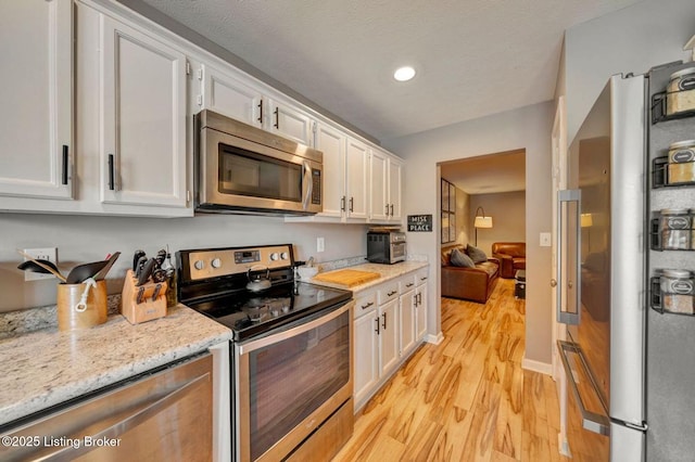5503 Forest Lake Dr, Prospect, KY 40059 - kitchen with appliances with stainless steel finishes, light wood-type flooring, white cabinetry, and light stone countertops
