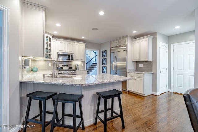 17503 Polo Run Ln, Louisville, KY 40245 - kitchen with stainless steel appliances, a peninsula, glass insert cabinets, decorative backsplash, and a breakfast bar area