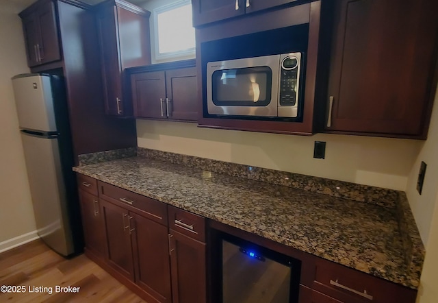 4318 Juniper Forest Pl, Louisville, KY 40245 - kitchen featuring stainless steel microwave, freestanding refrigerator, light wood-style flooring, wine cooler, and dark stone countertops