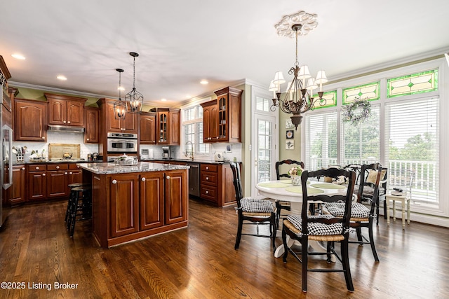 15018 Forest Oaks Dr, Louisville, KY 40245 - kitchen with a chandelier, under cabinet range hood, ornamental molding, a center island, and glass insert cabinets