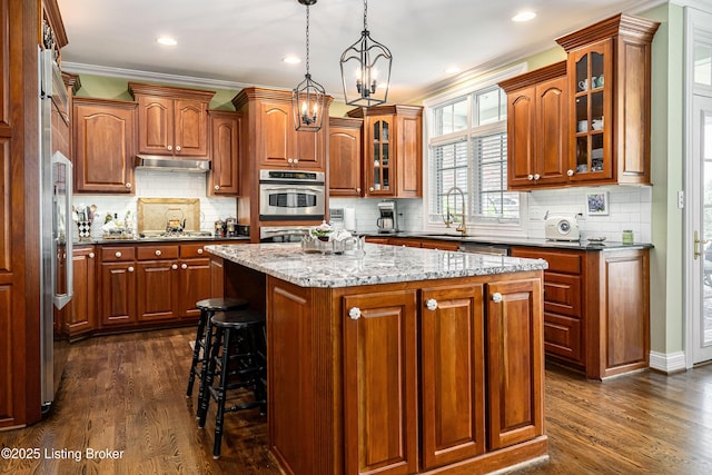 15018 Forest Oaks Dr, Louisville, KY 40245 - kitchen featuring crown molding, cooktop, a center island, brown cabinets, and dark wood-type flooring
