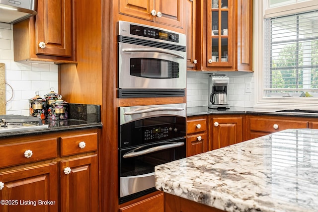 15018 Forest Oaks Dr, Louisville, KY 40245 - kitchen with brown cabinets, dark stone counters, glass insert cabinets, and decorative backsplash