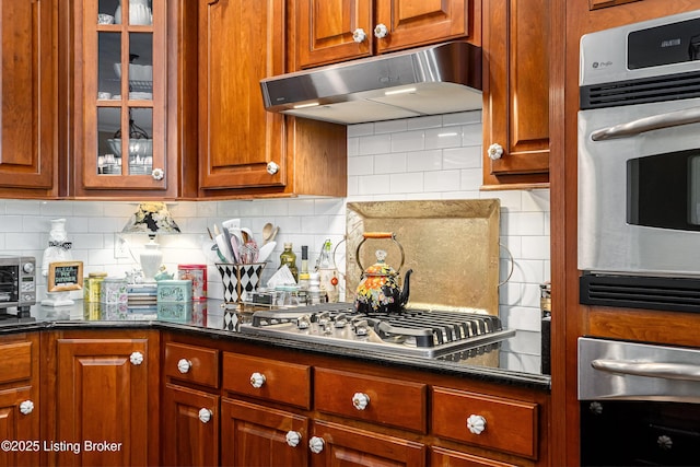 15018 Forest Oaks Dr, Louisville, KY 40245 - kitchen with under cabinet range hood, stainless steel appliances, glass insert cabinets, and tasteful backsplash