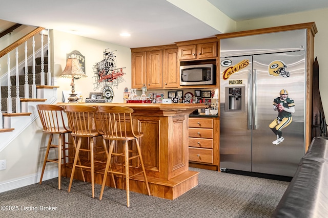 15018 Forest Oaks Dr, Louisville, KY 40245 - kitchen featuring appliances with stainless steel finishes, carpet flooring, a kitchen breakfast bar, brown cabinetry, and recessed lighting