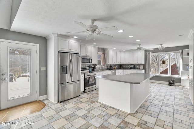 236 Running Creek Dr, Shepherdsville, KY 40165 - kitchen featuring appliances with stainless steel finishes, ceiling fan, white cabinetry, tasteful backsplash, and a kitchen island