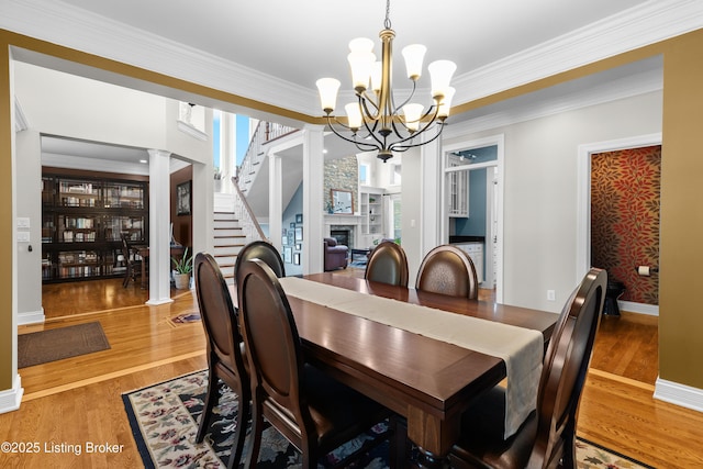 3111 Ridgemoor Ct, Prospect, KY 40059 - dining area with a chandelier, ornate columns, a fireplace, wood finished floors, and ornamental molding