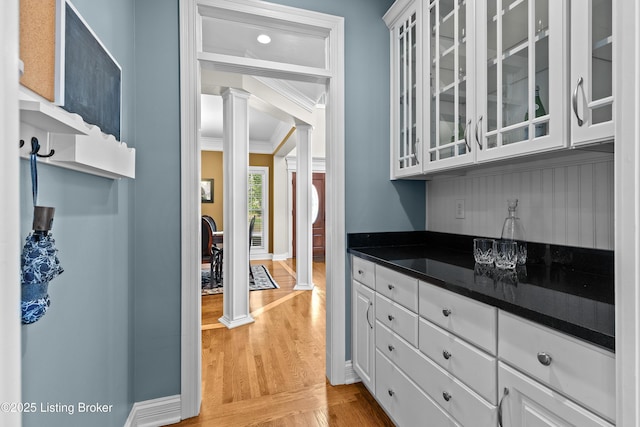3111 Ridgemoor Ct, Prospect, KY 40059 - kitchen with decorative columns, dark countertops, ornamental molding, light wood finished floors, and glass insert cabinets