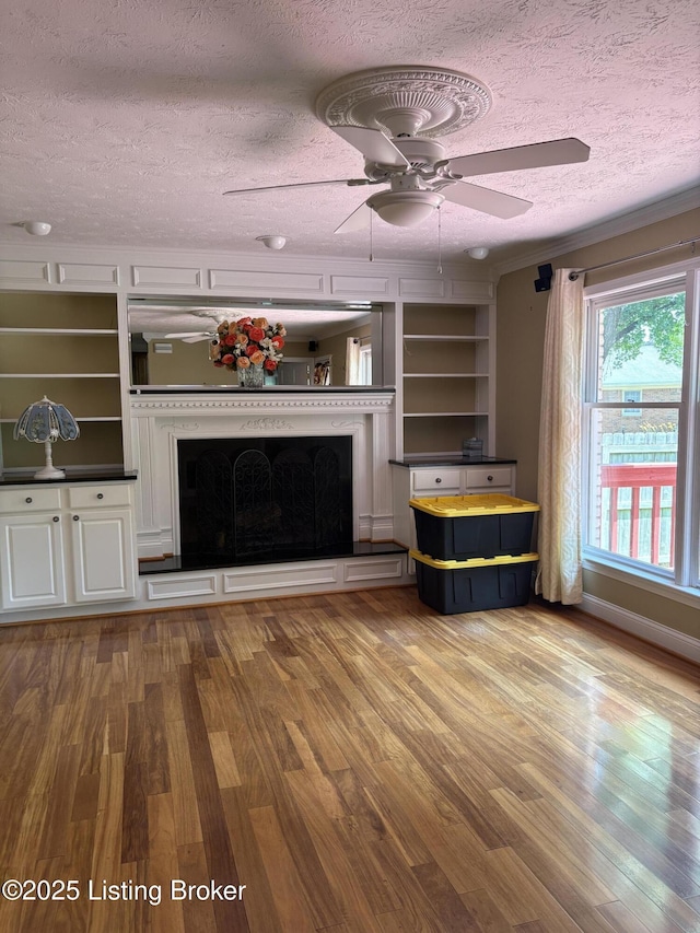 1303 Limestone Trce, Louisville, KY 40223 - unfurnished living room featuring a textured ceiling, wood finished floors, a fireplace with raised hearth, a ceiling fan, and built in shelves