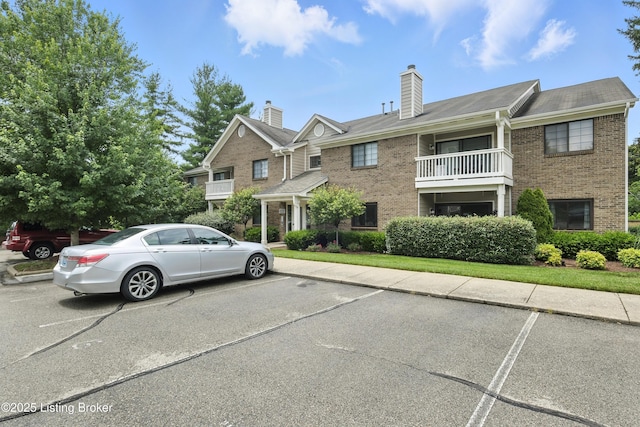 10500 Mcmeekin Ln Unit 208, Louisville, KY 40223 - view of front facade featuring brick siding, uncovered parking, a balcony, and a chimney
