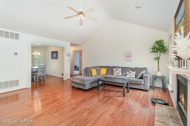2716 Antone Pkwy, Louisville, KY 40220 - living area featuring light wood-type flooring, lofted ceiling, a chandelier, ceiling fan, and a warm lit fireplace