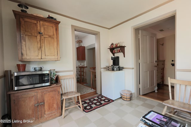 2406 Tucker Station Rd, Louisville, KY 40299 - kitchen with stainless steel microwave, light floors, light countertops, brown cabinets, and crown molding