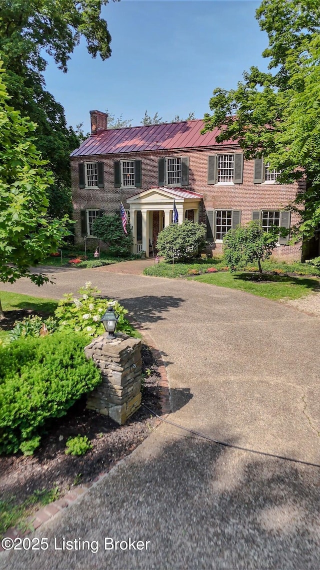2406 Tucker Station Rd, Louisville, KY 40299 - view of front of house with a chimney, a metal roof, brick siding, curved driveway, and a standing seam roof