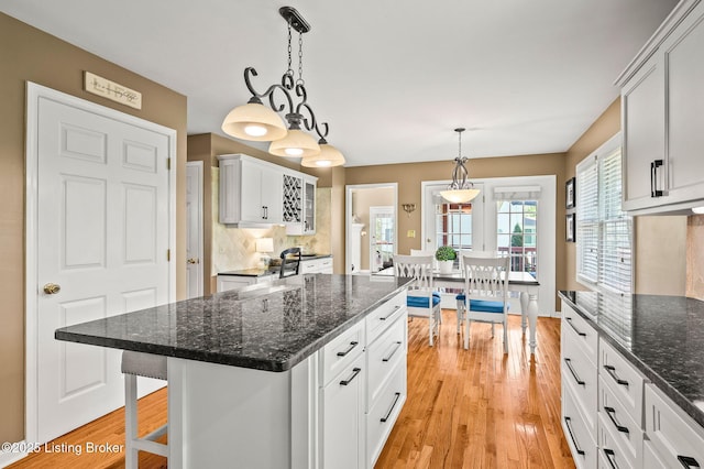 4423 Grand Cir, Crestwood, KY 40014 - kitchen featuring light wood-style flooring, white cabinets, a center island, pendant lighting, and dark stone counters