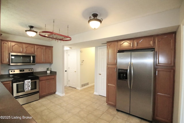 105 Wayne Way, Radcliff, KY 40160 - kitchen featuring stainless steel appliances, dark countertops, and brown cabinets