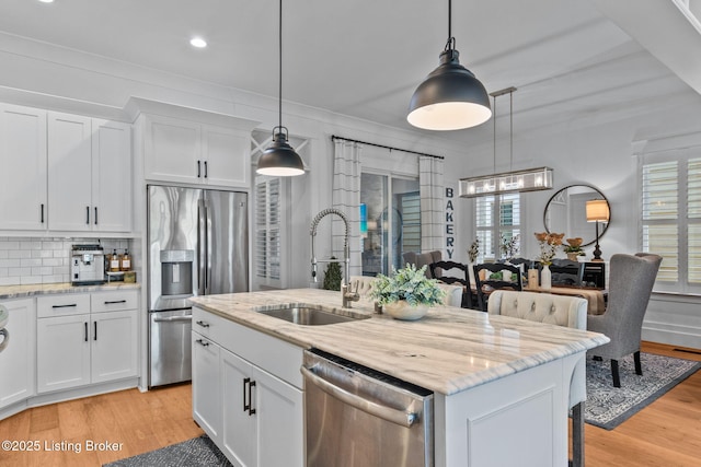 6331 Mistflower Cir, Prospect, KY 40059 - kitchen featuring stainless steel appliances, white cabinetry, light wood-style flooring, a center island with sink, and light stone countertops