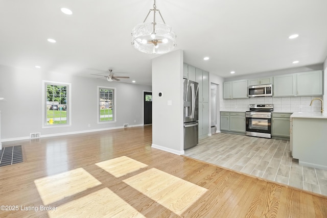6505 Ridge Cliff Rd, Hollow Creek, KY 40228 - kitchen with appliances with stainless steel finishes, light wood-style flooring, light countertops, a chandelier, and backsplash