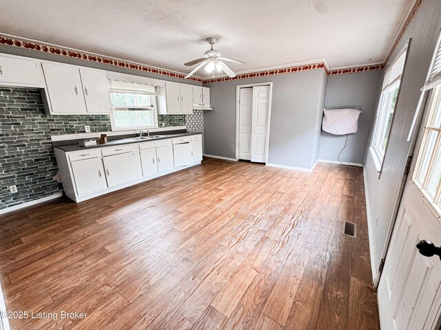 108 Bruce St, Lebanon Junction, KY 40150 - kitchen with dark countertops, a ceiling fan, light wood-style flooring, white cabinets, and decorative backsplash