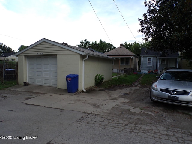 2113 Dumesnil St, Louisville, KY 40210 - view of front of home featuring concrete block siding, driveway, an outbuilding, a shingled roof, and a detached garage