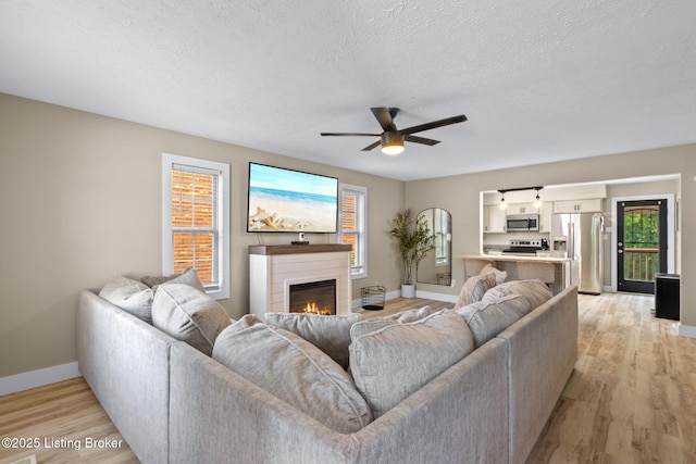 508 Auburn Oaks Dr, Louisville, KY 40214 - living room featuring a ceiling fan, light wood-type flooring, a textured ceiling, and a glass covered fireplace
