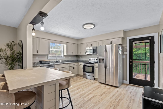 508 Auburn Oaks Dr, Louisville, KY 40214 - kitchen featuring stainless steel appliances, a kitchen bar, light wood-type flooring, a peninsula, and a textured ceiling