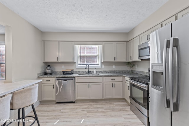 508 Auburn Oaks Dr, Louisville, KY 40214 - kitchen featuring appliances with stainless steel finishes, light wood-type flooring, a textured ceiling, and light stone countertops