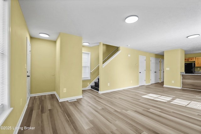 1601 Wilson Ave, Louisville, KY 40210 - unfurnished living room with light wood finished floors and stairway