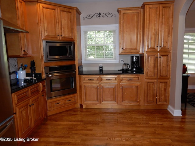 193 Pare Ct, Shepherdsville, KY 40165 - kitchen with appliances with stainless steel finishes, dark countertops, arched walkways, wood finished floors, and brown cabinetry