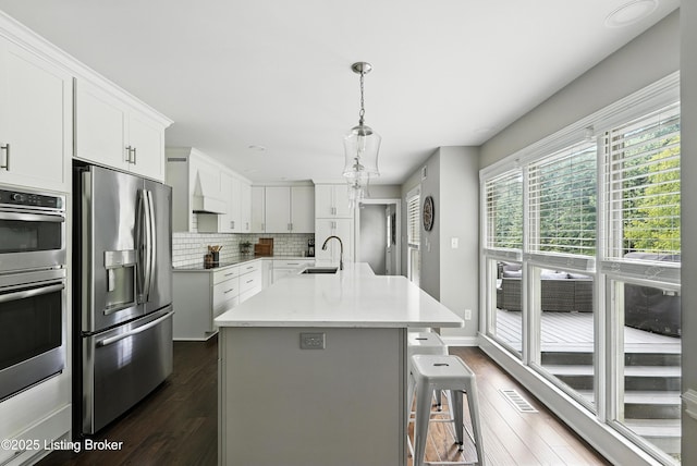 12512 Kirkham Rd, Louisville, KY 40299 - kitchen with stainless steel appliances, dark wood-style floors, tasteful backsplash, white cabinetry, and a breakfast bar