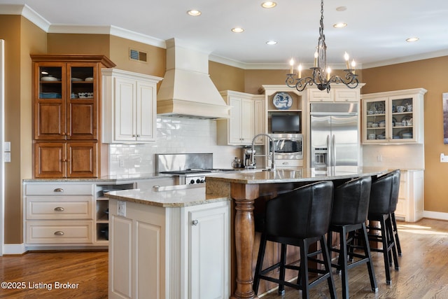 9906 Glen Vista Dr, Prospect, KY 40059 - kitchen with built in refrigerator, custom exhaust hood, stove, a center island with sink, and tasteful backsplash