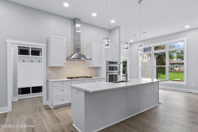 7103 Star Barn Ln, Crestwood, KY 40014 - kitchen with wall chimney range hood, stainless steel appliances, light countertops, white cabinets, and light wood-style floors