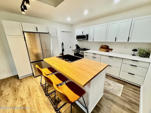 9068 Mackville Rd, Springfield, KY 40069 - kitchen featuring appliances with stainless steel finishes, light wood-type flooring, white cabinetry, a breakfast bar, and a center island