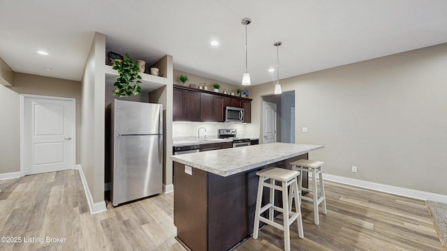 734 Dehart Ln, Louisville, KY 40243 - kitchen featuring stainless steel appliances, light countertops, dark brown cabinetry, a breakfast bar, and light wood-type flooring