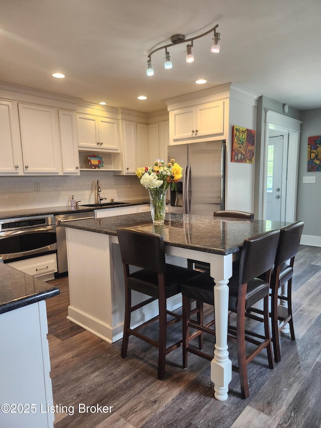 1860 Alfresco Pl, Louisville, KY 40205 - kitchen featuring appliances with stainless steel finishes, white cabinets, a center island, dark wood-style floors, and decorative backsplash