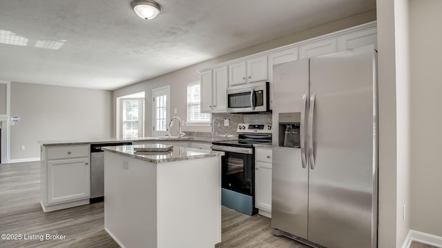4806 Middlesex Dr, Louisville, KY 40245 - kitchen with stainless steel appliances, a peninsula, a kitchen island, light wood finished floors, and white cabinetry