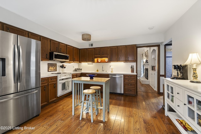 614 Armadale Pl, Douglass Hills, KY 40243 - kitchen with appliances with stainless steel finishes, light countertops, dark wood-style flooring, a breakfast bar, and a kitchen island