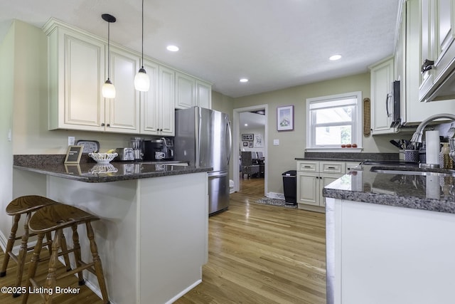 10703 Cedar Creek Rd, Louisville, KY 40229 - kitchen with freestanding refrigerator, a peninsula, light wood finished floors, a breakfast bar, and recessed lighting