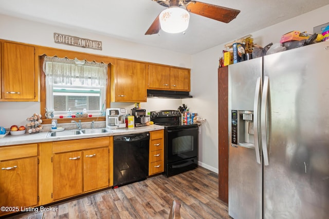 4418 Mann Ave, Louisville, KY 40215 - kitchen with black appliances, under cabinet range hood, wood finished floors, light countertops, and brown cabinets