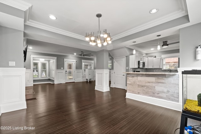 217 Shawnee Dr, Louisville, KY 40212 - unfurnished living room with a ceiling fan, a tray ceiling, a chandelier, crown molding, and dark wood-type flooring