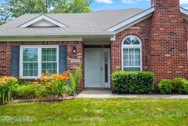 13702 Beowulf Ct, Louisville, KY 40299 - property entrance with roof with shingles, brick siding, a yard, and a chimney