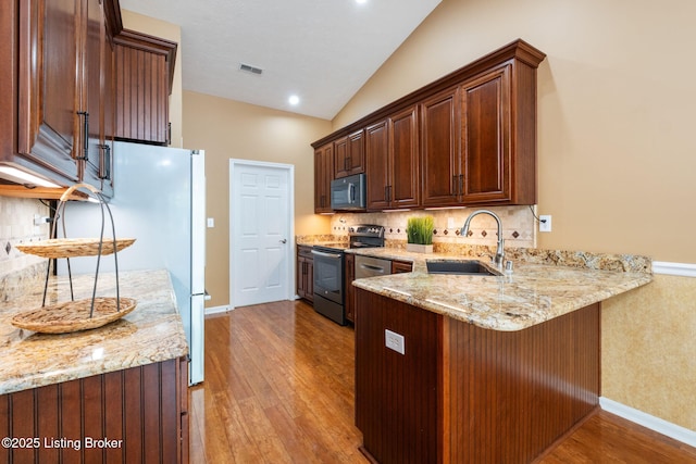 13702 Beowulf Ct, Louisville, KY 40299 - kitchen with stainless steel electric range, black microwave, a peninsula, wood finished floors, and lofted ceiling