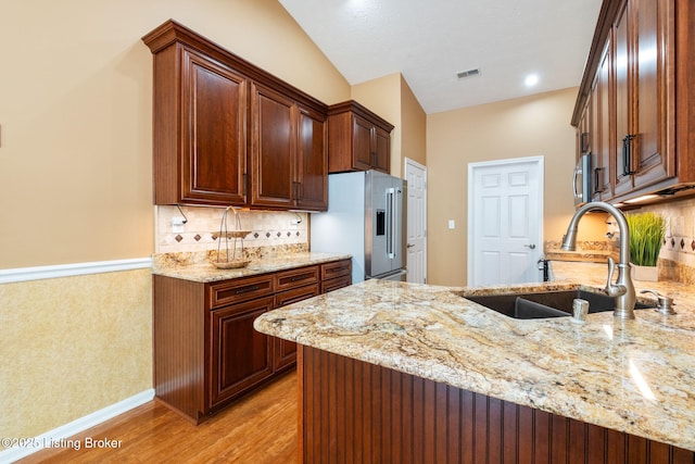 13702 Beowulf Ct, Louisville, KY 40299 - kitchen with stainless steel fridge with ice dispenser, light stone counters, light wood-type flooring, a peninsula, and tasteful backsplash