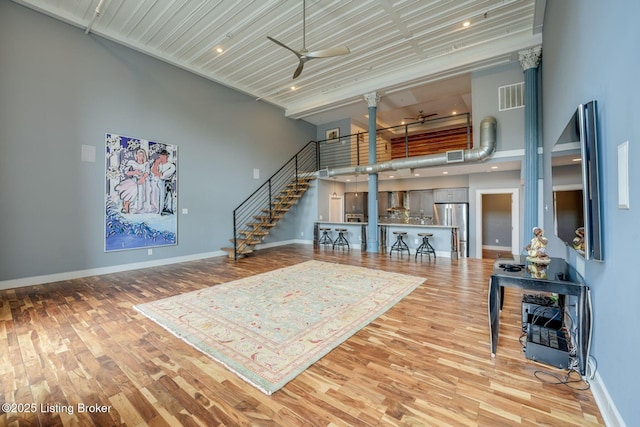 415 E Market St Unit 104, Louisville, KY 40202 - living area with decorative columns, ceiling fan, a high ceiling, light wood-type flooring, and stairs