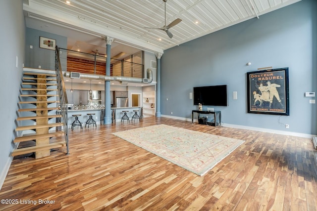 415 E Market St Unit 104, Louisville, KY 40202 - living area featuring ceiling fan, a high ceiling, wood finished floors, decorative columns, and stairway