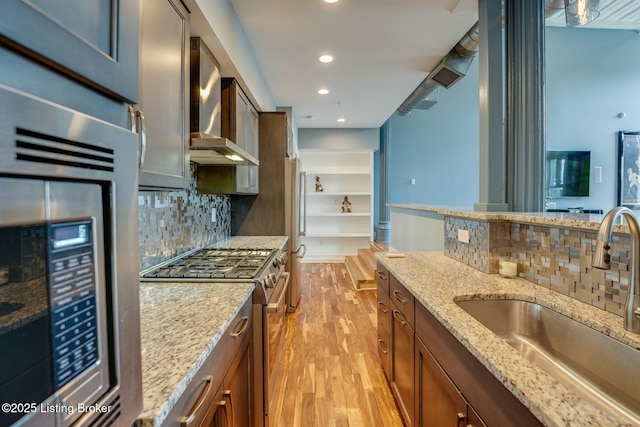 415 E Market St Unit 104, Louisville, KY 40202 - kitchen featuring stainless steel appliances, wall chimney range hood, light wood-type flooring, decorative backsplash, and recessed lighting